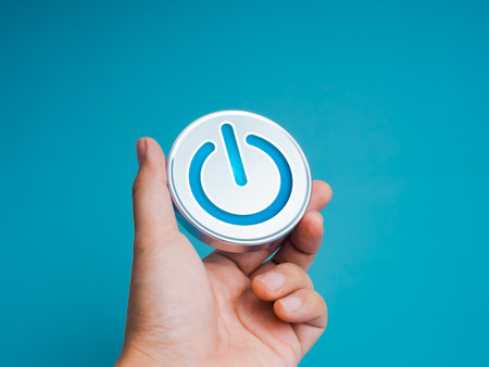 Power on, icon on chrome button or metallic badge in businessman hand, isolated on light blue...