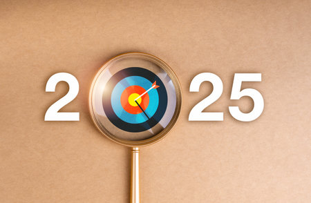 Happy new year 2025 with business trends and goal marketing concept. The big 2025 calendar number with bright colors target icon, focused in magnifying glass lens on brown background, minimal style.の写真素材