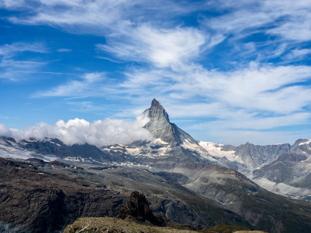 Landmark scene of Matterhorn peak in the Swiss Alps. Amazing view of Matterhorn with white puffy cloud on blue sky background. Tourist destination with summer mountains in Switzerland.の写真素材