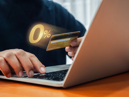Shopping online with special offer installment payments. Zero percent rate appear on credit card, holding by businessman's hand, who working with laptop computer. 0% Interest free, zero commission.の写真素材