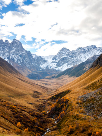 Beautiful autumn hills with small stream, near Caucasus mountains background with snow peak, walking...