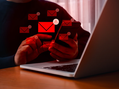 SMS or email spam, fake text message phishing from scammer concept. Many red envelope with system hacked warning alert icon, scam malware spreading virus on message showing on mobile phone in hand.の写真素材