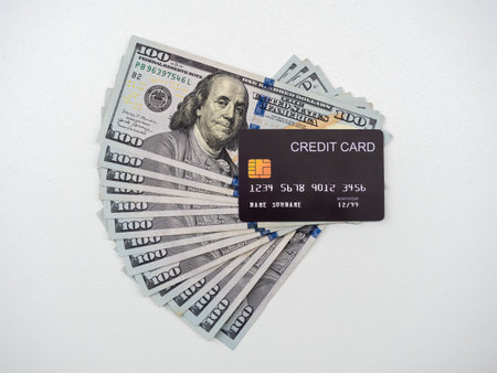 Fake black credit card on many 100 Dollar banknotes cash, isolated on white background. Money fan,...