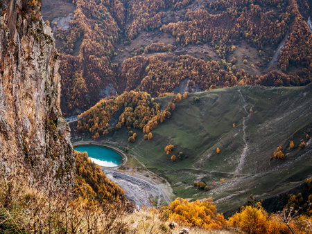 Round lake deep in a valley with autumn trees, yellow , green color covered the mountains, near the...