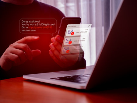 SMS spam, fake text message phishing scammer concept. Winning congratulations phishing, text with link tracking, on message alert display on mobile phone screen in hand, messages from unknown number.の写真素材