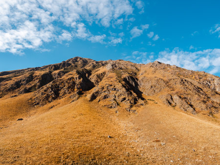 Rock mountain peaks on autumn hills on blue sky and cloud background on sunny day, walking view at...