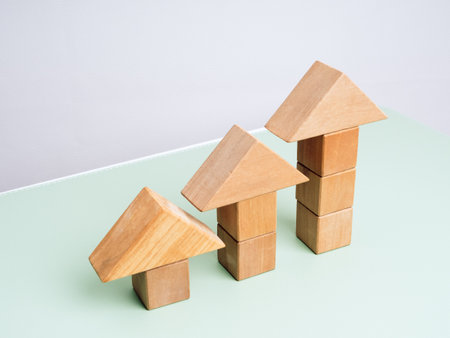 Three wooden arrowhead built by cube blocks as bar graph chart steps on green table, white background. Business growth, Investment, income develop, trends, leadership, economic improvement concepts.の写真素材