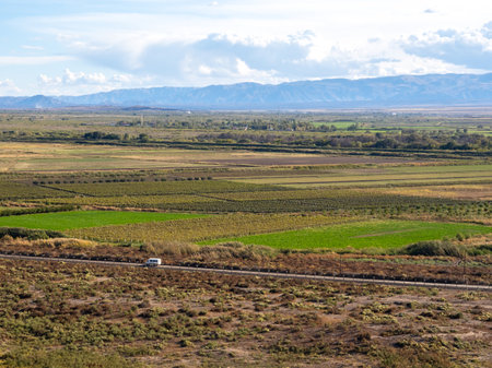 White van on the road with beautiful landscape with agriculture farm and green fields on blue sky...