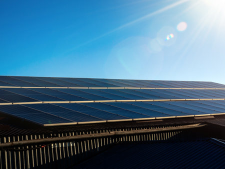 Solar panels on house roof with morning sun rays on blue sky background with copy space....