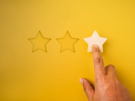1 star rating reviews button pressed by hand on yellow background. Poor customer satisfaction, low evaluation, negative feedback, specific service or experience survey, business marketing concepts.の写真素材