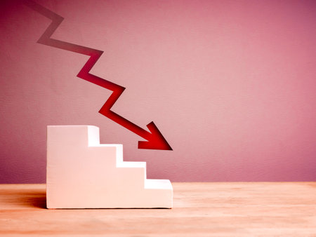 Crisis chart and graph. Economic downturn with decrease arrow on white empty steps as graph on wood table, red background with copy space. Business volatility trend process, financial concept.の写真素材