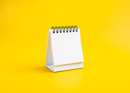 Blank space of white page of desk spiral calendar for organizer concept to plan and reminder, isolated on yellow background. Mock up small table calendar paper, template for date and month design.の写真素材