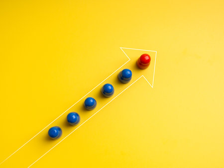 Boss and employee, the red one leading at front the group of blue peg dolls, stand in forward arrow line shape, on yellow background. Leadership, unique, influencer, teamwork, team building concept.の写真素材