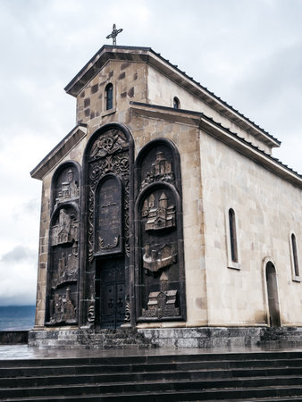 Orthodox church at monument on rainy day, famous tourist attraction, located on Keeni hill near the Tbilisi sea, Georgia, with white fog sky after rain day, vertical photo.の写真素材