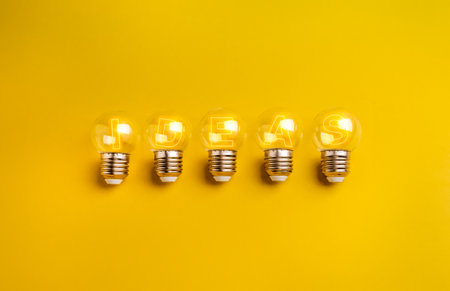 Five glowing small clear light bulbs with shining text IDEAS inside, isolated on yellow background....