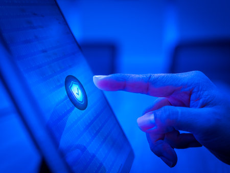 Blue safety shield icon on cyber network background on computer screen while finger scanning for access with biometrics identification. Cyber security, privacy data protection technology concept.の写真素材