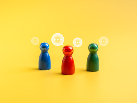 AI assistant, business and technology, teamwork and team building concept. Red, green and blue peg dolls with chatbot face icon, standing together with conversation on yellow background, minimalist.の写真素材