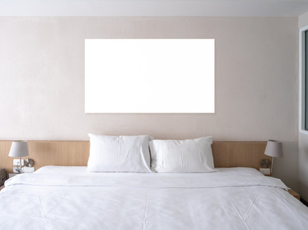 Mockup empty space blank square frame hanging on white wall background over wooden bed with pillows and clean blanket, decoration with lamps in hotel room background, no people.の写真素材