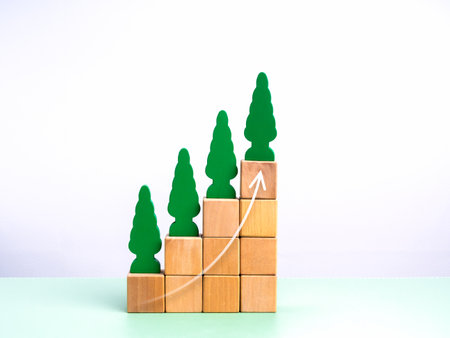 Green business and environmental, agriculture concept. Rise arrow on tree growth, eco wooden toys on wood cube blocks, arranged as graph steps, chart diagram, isolated on white background, minimalist.の写真素材