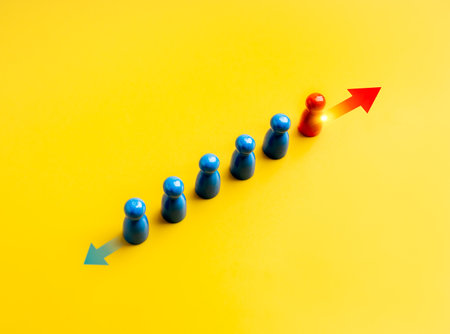 Different ways, difference, unique, business solution concept. The brave red one peg doll moving opposite of other blues, with arrow direction signs, on yellow background. Stand out from the crowd.の写真素材