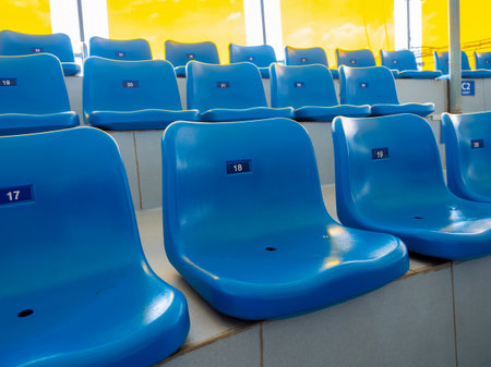 Scene of seat numbers on empty blue plastic chairs, in stadium or aquarium show. Rows of seats pattern, on the steps with no people.の写真素材