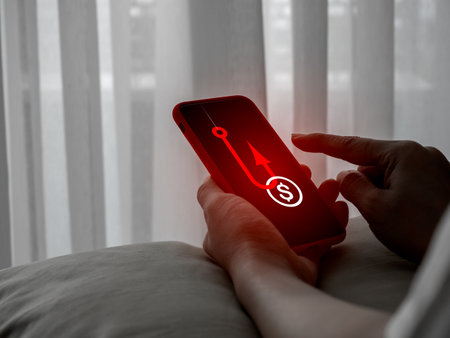 Scammer attack with benefit phishing concept. Coin with hook, cryptocurrency or financial scams tactic, showing on mobile phone screen in victim hands who online, social networking, often cyberattack.の写真素材