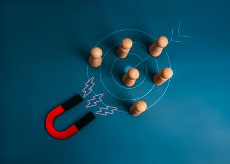 Digital marketing, target audience, Customer attraction concept. Big horseshoe magnet attracting wooden figure group on target icon, blue background. Business team building, recruitment concept.の写真素材