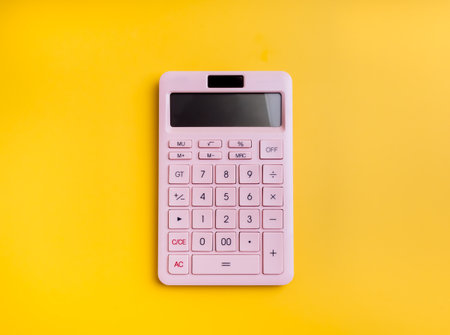 Top view of modern pink heating calculator on yellow background, flat lay, minimal style. Financial tool, business calculation, budget planning, startup tools, finance accounting concept.の写真素材