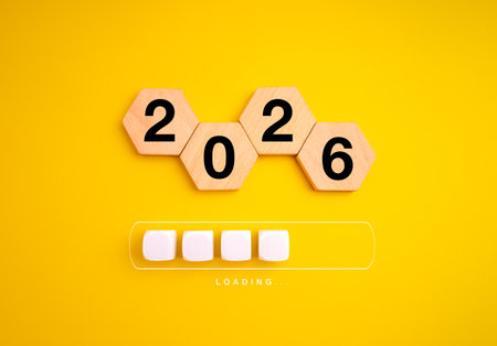 Wooden hexagons show 2026 above loading bar on yellow background, symbolizing upcoming year, new...