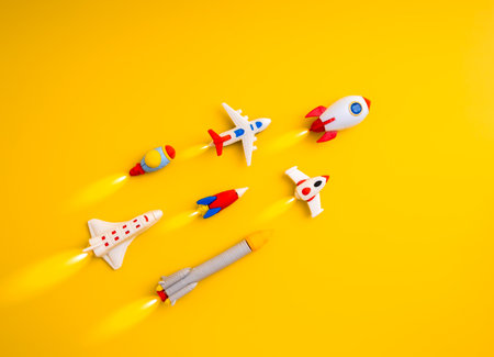 Colorful toy rockets and airplanes flying upward on yellow background. Concept of growth and success, startup launch, innovation, creative thinking, new business ideas and entrepreneurship journey.の写真素材