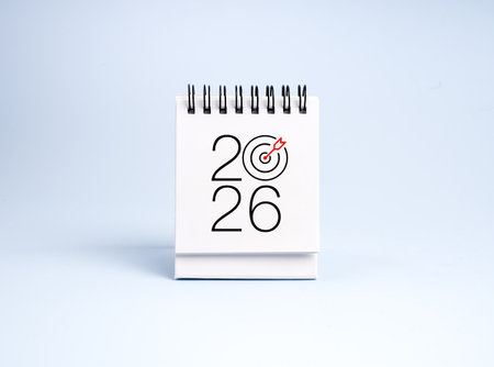 2026 white desk calendar with red arrow hitting target icon symbolizes new year business goals, trends, vision, action planning, strategy, success achievement, and corporate growth vision for 2026.の写真素材
