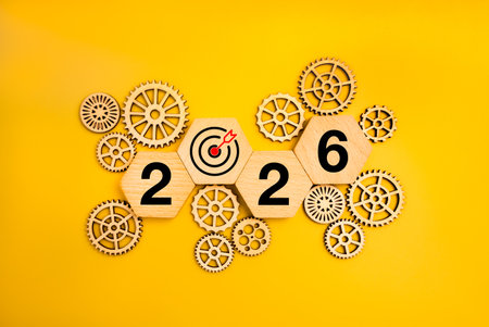 2026 new year numbers on hexagon wooden blocks with many gear wheels on yellow background,...
