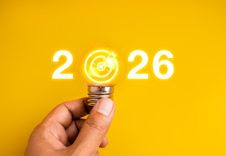 Creative business goal 2026 concept with hand holding glowing lightbulb and target dartboard icon on...