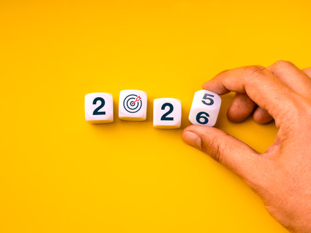 Concept of changing business goals for 2026 with hand flipping dice from 2025 to 2026 and target...