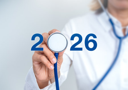 Doctor in white coat holding stethoscope with blue number 2026 on white background, symbolizing...