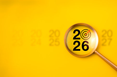 Magnifying glass focusing on number 2026 with target icon on yellow background. Concept for new year focus, business goals, trends, planning, strategy, vision, success, and future opportunities.の写真素材