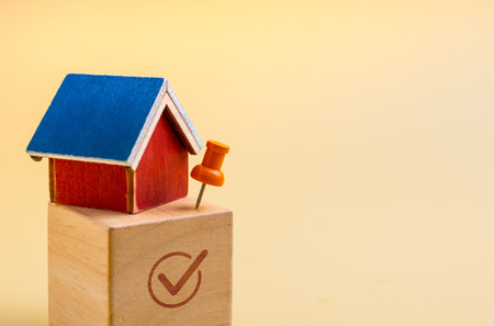 Mini house model with push pin on wooden block and check mark symbol with space. Concept of real estate investment, property choice, location selection, housing market decision and financial planning.の写真素材