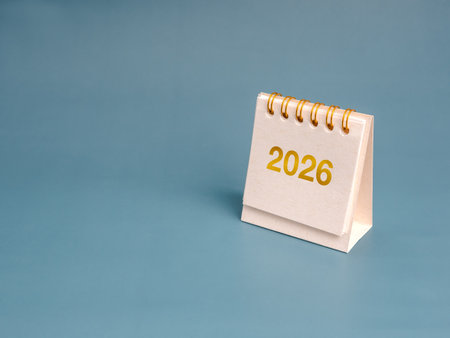 Desk calendar showing year 2026 on blue background symbolizing new year celebration, future planning, annual goals, fresh opportunities, business schedule, timeline, and personal development concept.の写真素材