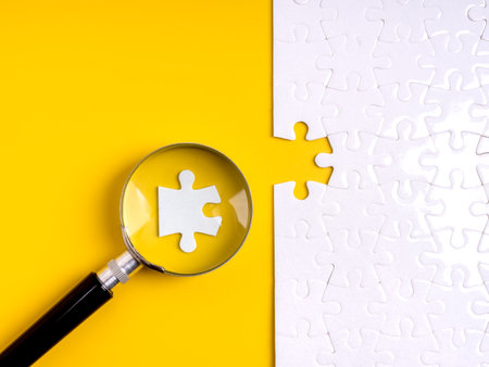 Magnifying glass focusing on puzzle piece fitting into missing part. Concept for hiring, human resource selection, recruitment, team building, employee match, workforce planning and business solution.の写真素材