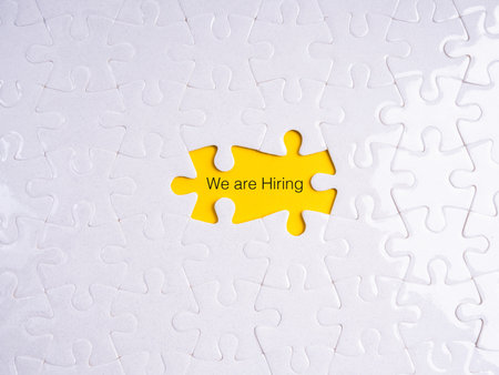 Hiring and recruitment concept with puzzle piece missing showing yellow background and text We are Hiring, symbolizing job vacancy, employment opportunity, HR search, career growth, and team building.の写真素材