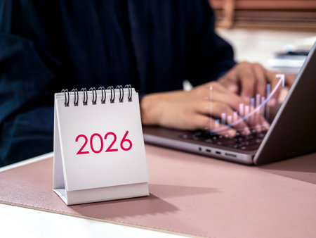 White desk calendar showing 2026 with businessman working on laptop and graph growth. Concept of financial planning, investment strategy, business development, economic forecast, and new year success.の写真素材