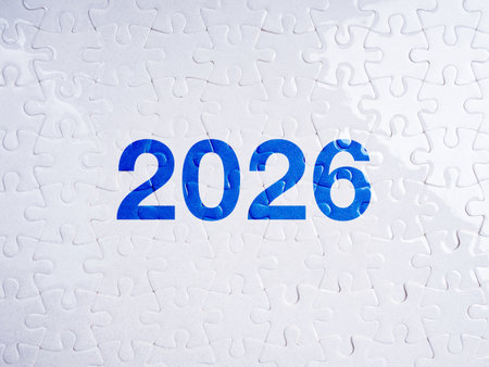 Completed white puzzle pieces forming number 2026 in blue, symbolizing new year business goals,...
