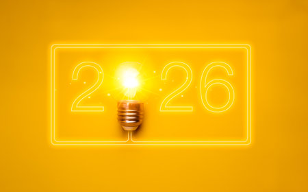Creative innovation concept for new year 2026 with numbers connected glowing light bulb on yellow background. Symbol of new ideas, inspiration, future thinking, startup goals and creative resolutions.の写真素材
