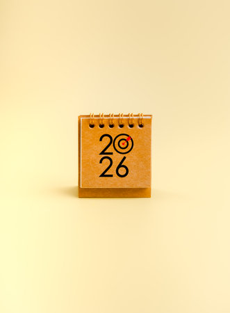 New year 2026 planning concept with yellow ochre desk calendar showing target symbol. Represents business goals, work strategy, fresh start, productivity mindset, and goal setting for the new year.の写真素材