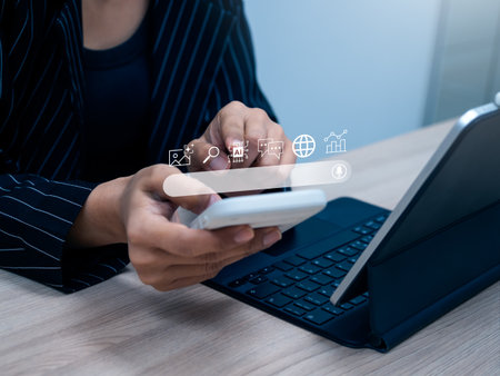 Close-up of hands using smartphone with AI chatbot and search interface, representing smart assistant technology, digital lifestyle, online search behavior, and artificial intelligence communication.の写真素材