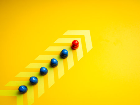 Leadership concept with red figure leading blue team figures forward on arrow path on yellow background. Symbolizes team direction, business leadership, innovation, and strong vision for success.の写真素材