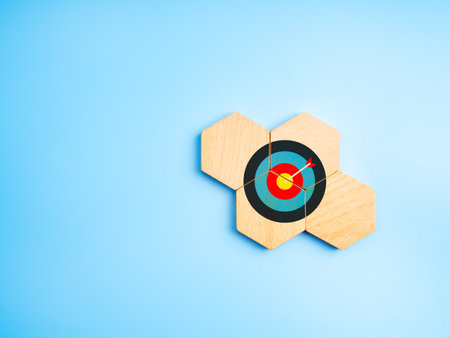 Target board on wooden hexagon puzzle pieces symbolizing aligned goals, stakeholder collaboration,...