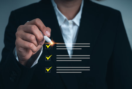 Businesswoman using digital pen to mark checklist items on virtual interface, representing verification, task management, auditing, project review, and quality assurance in modern business.の写真素材