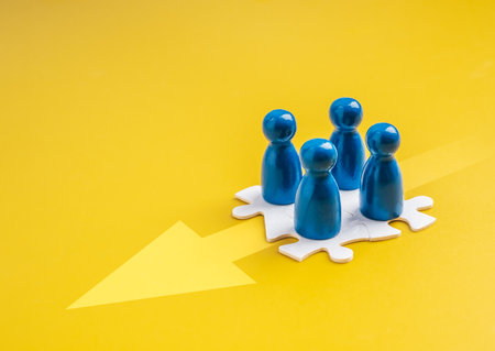 Blue human figures on puzzle pieces, forward arrow represent teamwork, stakeholder alignment, cooperation, partnership, organizational synergy and group collaboration toward common goal or direction.の写真素材