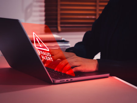 Business person or user receiving a red fraud alert warning on virtual screen. Cybersecurity risks, financial fraud, online scams, scammer attack, data breaches, and digital security threats concept.の写真素材